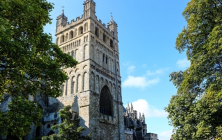 Die Exeter Cathedral in England zeigt beeindruckende gotische Architektur, umgeben von Bäumen und klarem Himmel im Stadtzentrum.
