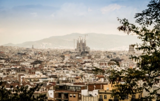 Blick über die Stadt Barcelona mit der Sagrada Família, umgeben von Hügeln, ideal für einen kulturellen Familienurlaub.